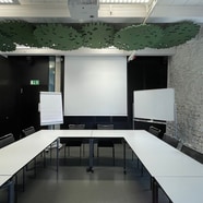 Konferenzraum mit Tischen in U-Form und Beamer.