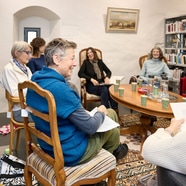 Menschen sitzen in einem Bibliotheksraum und unterhalten sich über Literatur.
