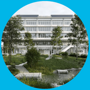 Modernes Gebäude mit Bäumen und Rasen im Vordergrund.