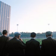 Männer stehen im Vordergrund, blicken auf das Sportstadion Schützenwiese bei Sonnenuntergang.