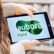 Person hält ein Tablet mit Logo auf dem Bildschirm.