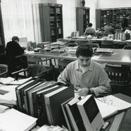 Menschen in einer Bibliothek mit Tischen voller Bücher.