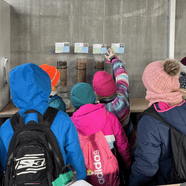 Kinder in bunten Jacken schauen sich Ausstellung an.