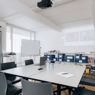 Besprechungsraum mit Tisch, Stühlen und Whiteboard.