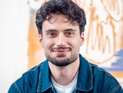Mann mit lockigem Haar lächelt.