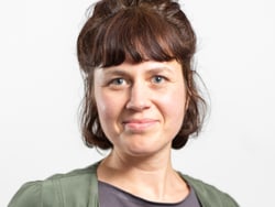 Person mit braunen Haaren und grünem Oberteil vor weissem Hintergrund.