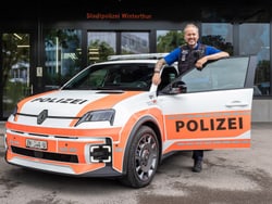 Person neben Polizeiauto mit offener Tür.