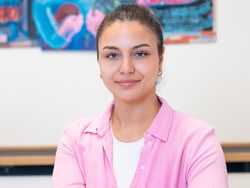 Person in rosa Hemd vor einem farbenfrohen Kunstwerk.