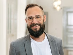 Mann mit Bart und Brille lächelnd.