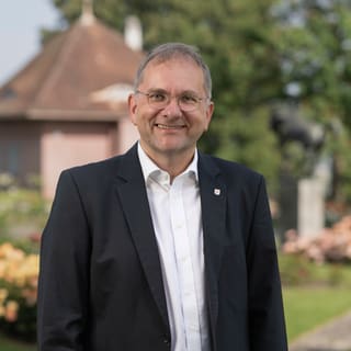 Stadtpräsident Stefan Fritschi steht in einem Garten mit Blumen und Pavillon.