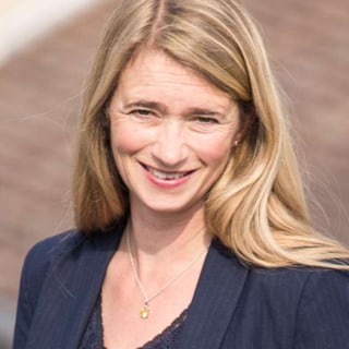 Frau mit langen blonden Haaren im Freien, trägt Blazer.