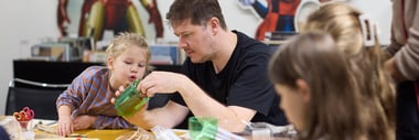 Erwachsener und Kinder basteln an einem Tisch.
