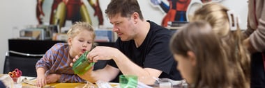 Erwachsener und Kinder basteln an einem Tisch in der Bibliothek.