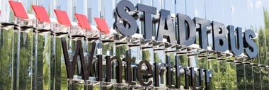 Schriftzug 'Stadtbus Winterthur' auf reflektierender Oberfläche des Busdepots an der Grüzefeldstrasse.