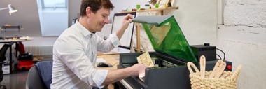 Person in weissem Hemd arbeitet an einem Tisch mit einem Laser Cutter.