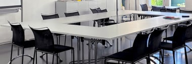 Leerer Besprechungsraum mit Tisch und Stühlen.