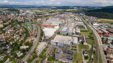 Luftaufnahme einer Stadt mit Gebäuden, Strassen und Bahnschienen.