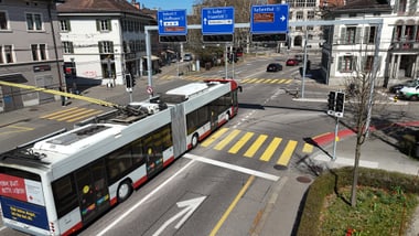 Bus an einer Strassenkreuzung mit Wegweisern und Lichtsignalanlagen