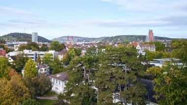 Stadtansicht mit Gebäuden und Bäumen unter blauem Himmel.