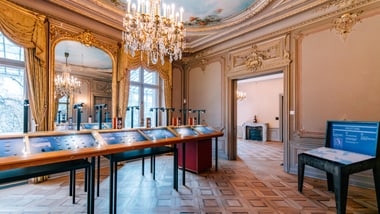 Eleganter Raum mit Kronleuchtern und Ausstellungsstücken.