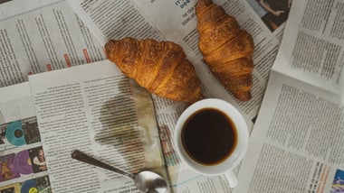 Zwei Croissants und eine Tasse Kaffee auf Zeitungen.