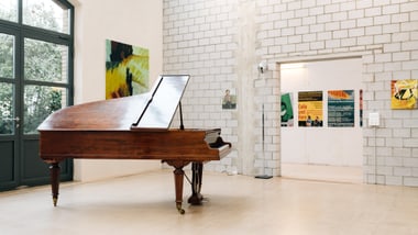 Flügel in einem Raum mit Kunstwerken an den Wänden.