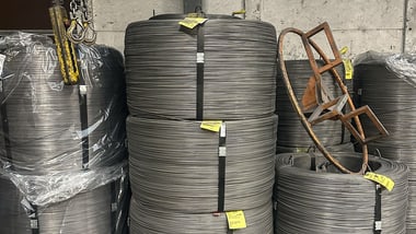 Gestapelte Rollen aus Metallkabeln in einem Lagerbereich.