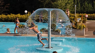 Kinder spielen in einem Pool mit Wasserspiel.