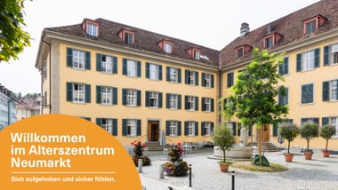 Grosses gelbes Gebäude mit Innenhof und Bäumen.