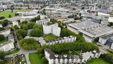 Luftaufnahme einer städtischen Landschaft mit Wohnhäusern und Grünflächen.