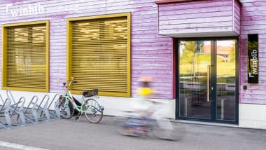 Aussenansicht der Bibliothek Hegi mit lila Holzfassade und Fahrradständern