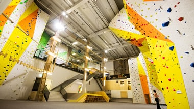 Innenansicht einer Kletterhalle mit bunten Wänden und Griffen.
