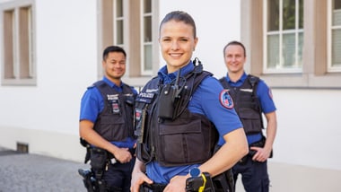 Drei Polizisten in Uniformen vor einem Gebäude.