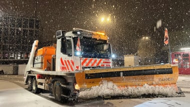 Schneepflug räumt nachts die Strasse.
