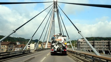 LKW fährt über eine Brücke mit Seilen.