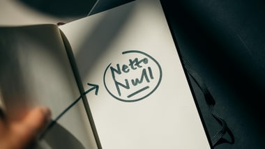 Nahaufnahme eines Notizbuchs mit handgeschriebenen Worten "Netto Null" und Pfeil.