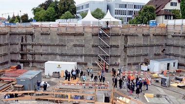 Baustelle mit mehreren Personen und Baucontainern.