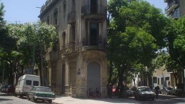 Ecke einer Strasse mit altem Gebäude und parkenden Autos.