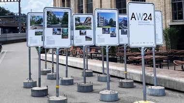 Reihe von Infotafeln vor einem Backsteingebäude.