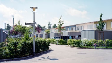 Wohngebiet mit Reihenhäusern, Strassenlaterne und Büschen.