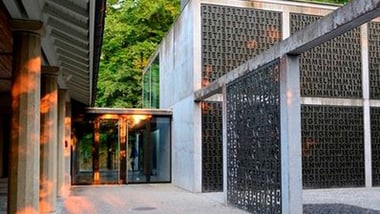 Gebäude mit Glasfenstern und dekorativen Metallwänden bei Sonnenuntergang.