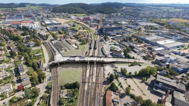 Luftaufnahme eines Bahnhofs und umliegender Stadtlandschaft.