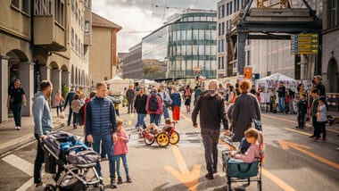 Menschen spazieren auf einer Stadtstrasse bei einem Strassenfest.