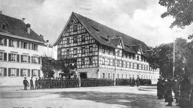Historisches Gebäude mit Personen in einer Reihe davor.