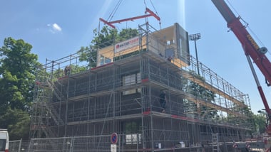 Baugerüst mit Kran auf Baustelle bei klarem Himmel.