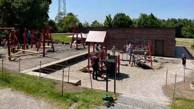 Spielplatz mit Schaukeln und mehreren Menschen.
