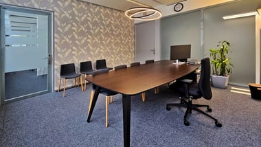 Konferenzraum mit Tisch, Stühlen und Pflanze.