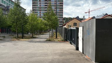 Städtische Szene mit Hochhaus, Bäumen und Baukran.