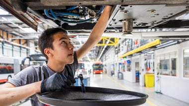Ein Lernender arbeitet unter einem Fahrzeug in der Werkstatt.