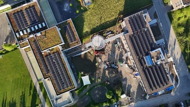 Luftaufnahme vom Schulhaus Wyden mit Solarpanelen und Baustelle.